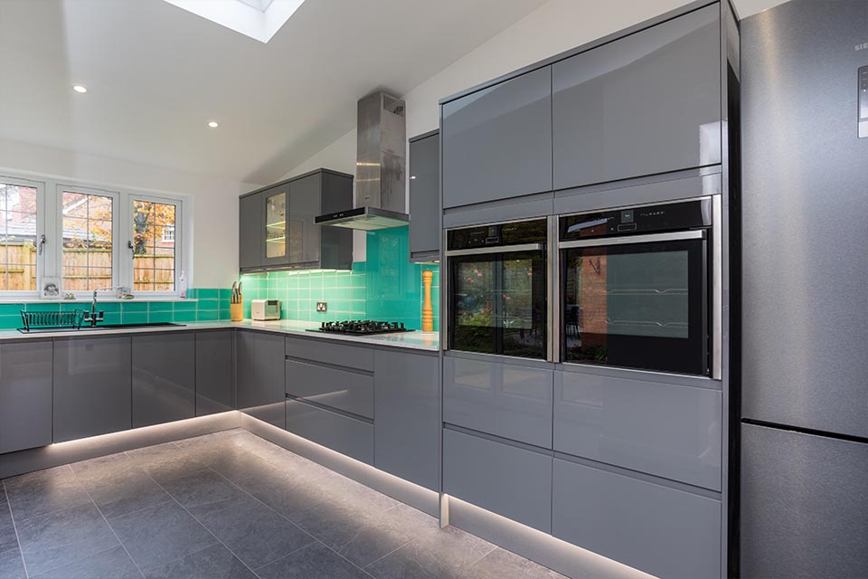 A newly installed kitchen with grey cupboards and turquoise tiled splashback.