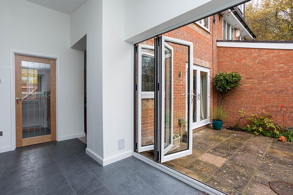 The rear patio of a semi-detatched house as soon through large open folding doors.