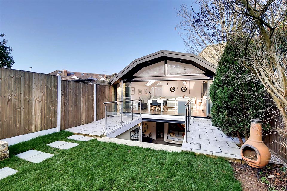 A garden office building with a basement showing the full width folding doors in the open position.