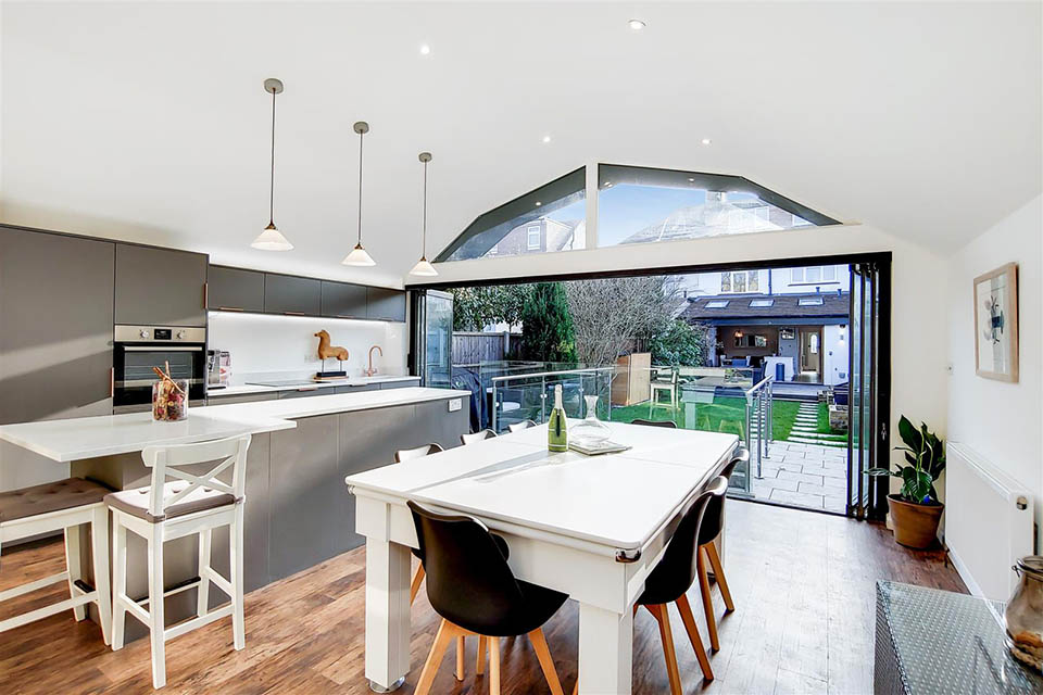 A garden building showing a newly installed kitchen area with dining table and breakfast bar.