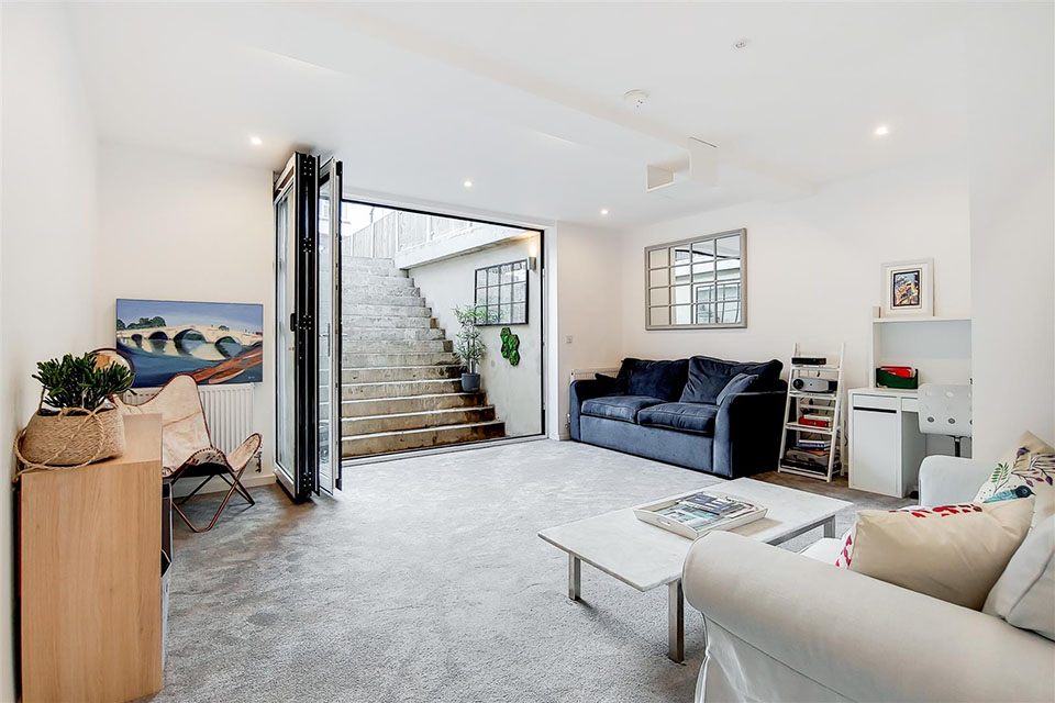 A newly built garden building showing a basement seating area with folding doors leading back up to ground level.