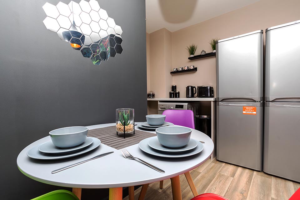 Table and chairs and two large fridge freezers in a multiple occupancy house.