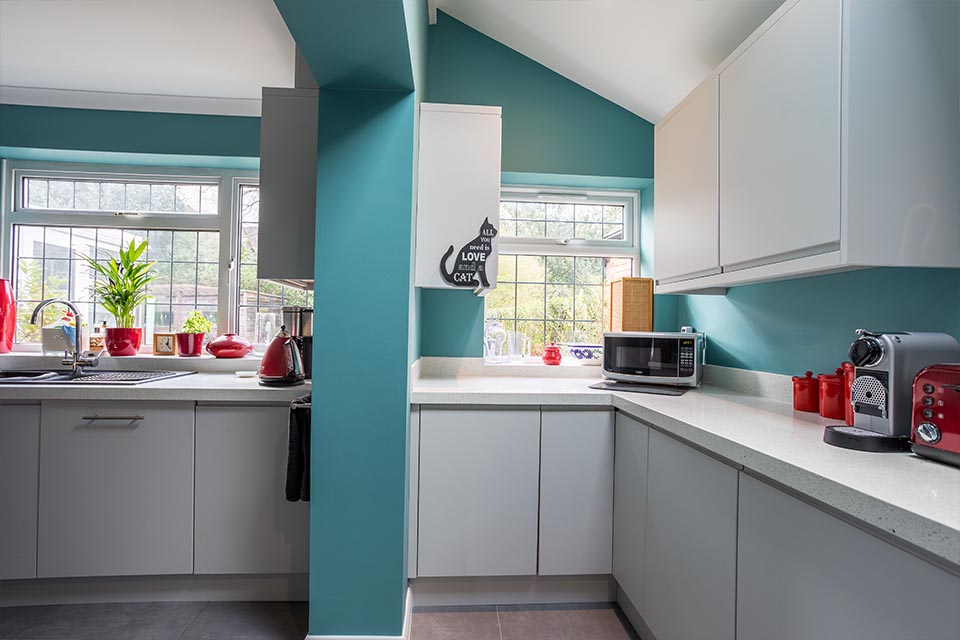 A kitchen extension with white cupboards and nordic blue walls.