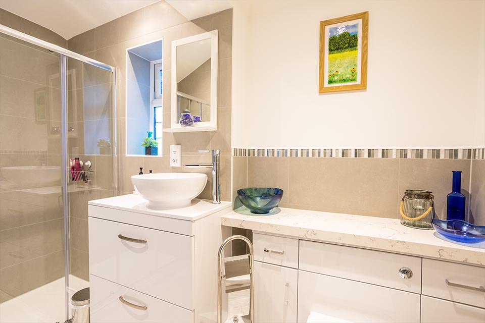 A brand new bathroom with white cupboards and a large step-in shower.