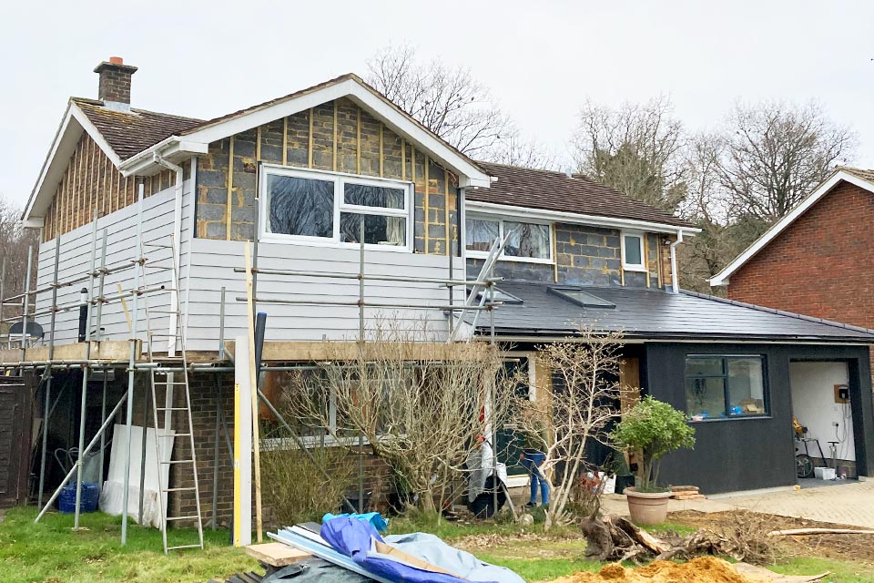 A detatched house with a newly built wrap around extension. The house is in the process of having the cladding replaced.