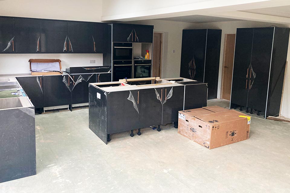A new kitchen being installed with black cupboards.