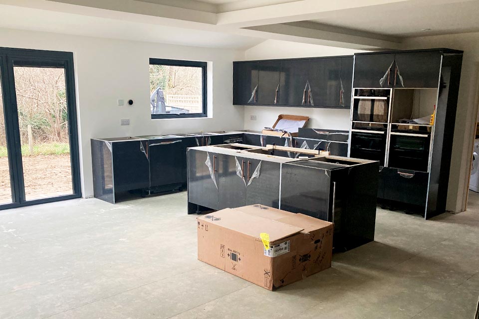 A new kitchen with black furniture being installed.