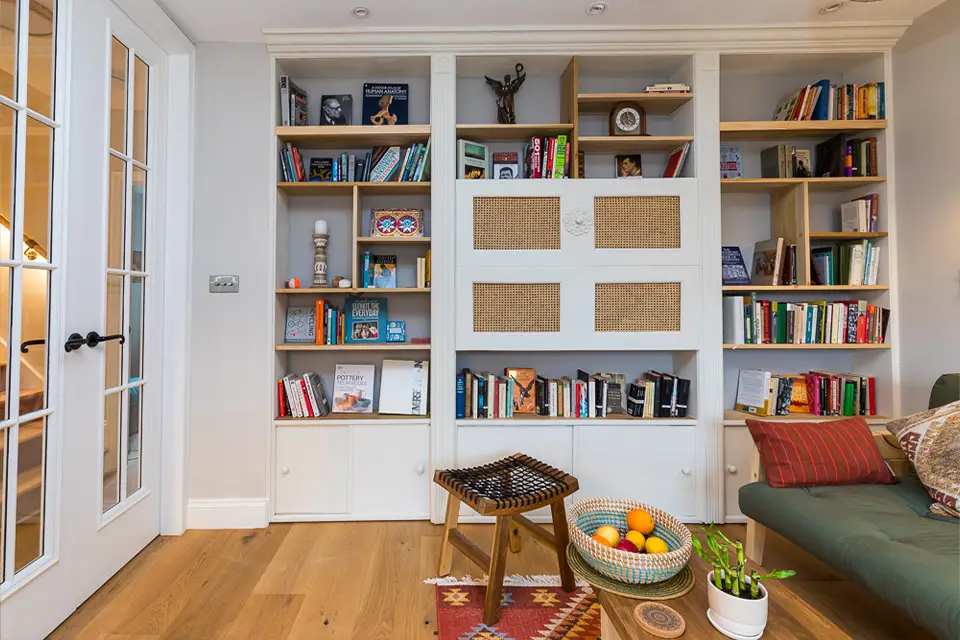 A living room interior with fitted bookshelves. There is a secret door hidden in the bookshelves and is currently closed.