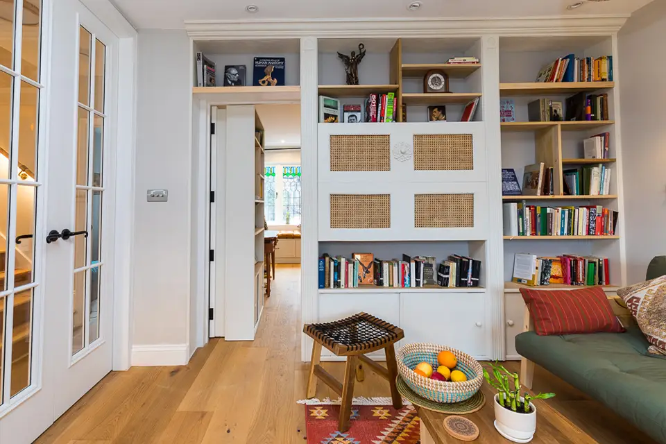 A living room interior with fitted bookshelves. There is a secret door hidden in the bookshelves leading through to the front room.