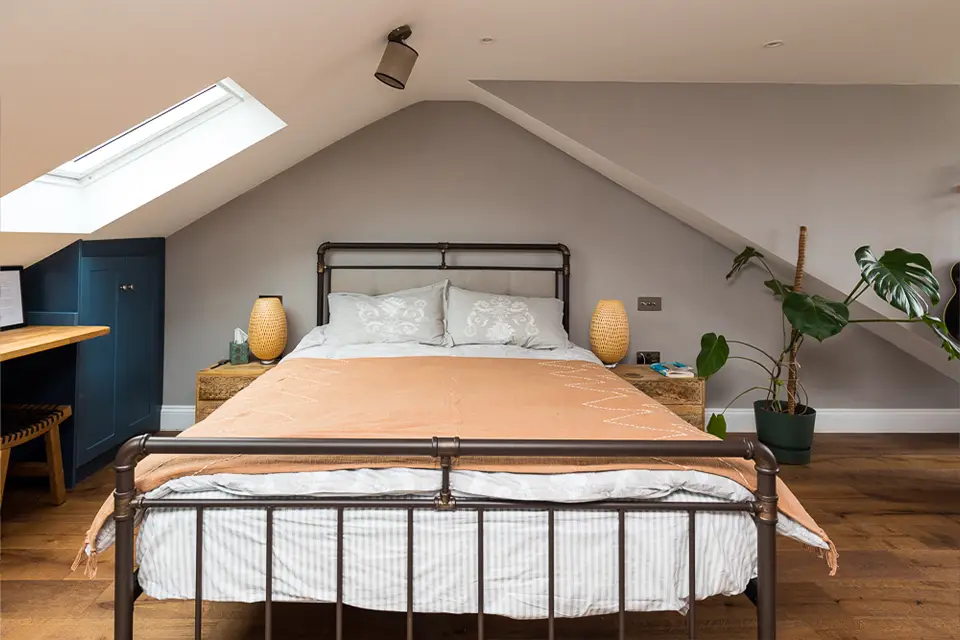 A large bedroom space showing the bed in the apex of the roof in a loft conversion.